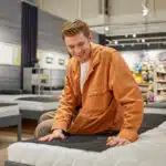 un jeune homme en train d'acheter un matelas en magasin