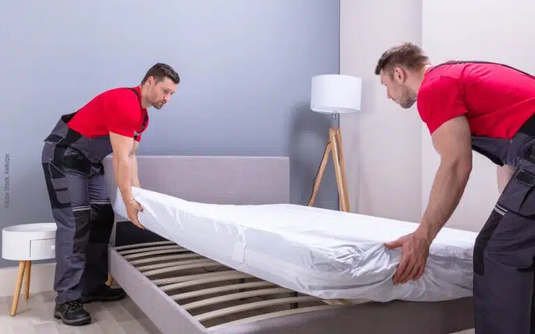 des livreurs posent un matelas neuf sur un sommier