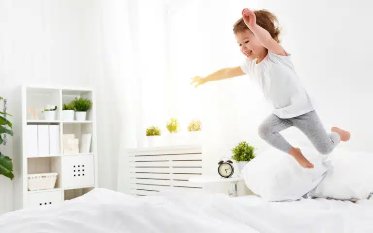 un enfant joyeux plonge sur un lit