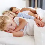 un enfant dort à poings fermés