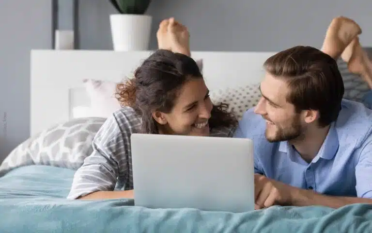 un jeune couple avec son ordinateur sur le lit