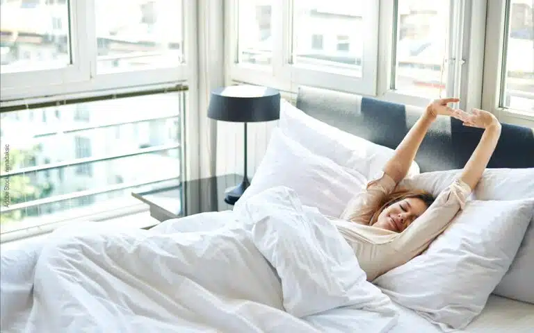 Une jeune femmes s'étire dans son lit