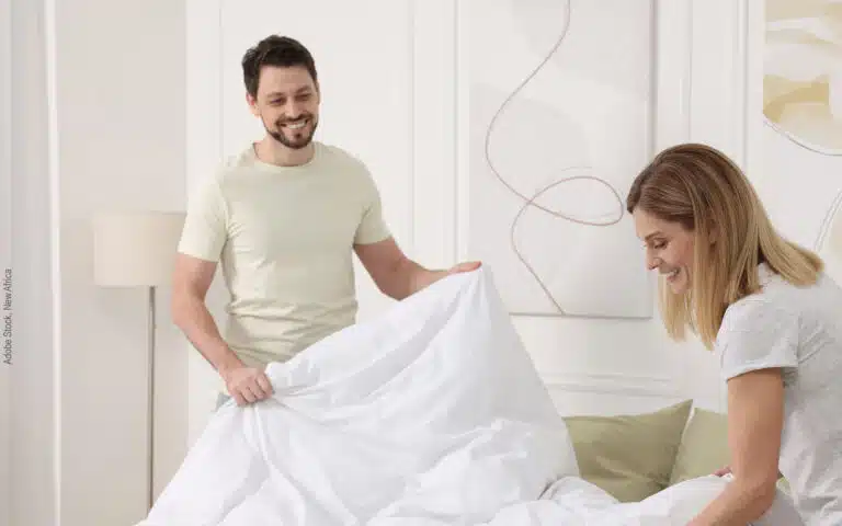 un couple installe une couette synthétique sur son lit