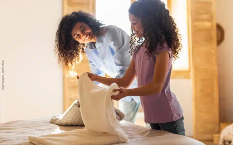 une jeune fille plie du linge sur son lit