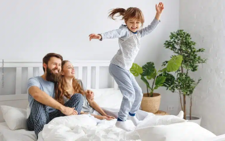 une petite fille saute sur le lit de ses parents