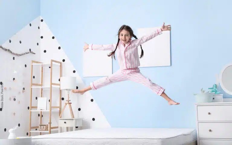 petite fille en pyjama qui saute sur son matelas