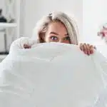 une jeune femme se cache sous sa couette