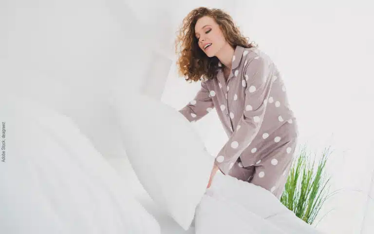 une jeune femme en pyjama refait son lit