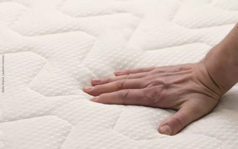 une main caresse le coutil d'un matelas