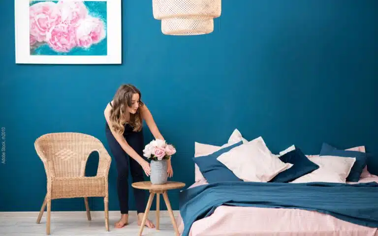une jeune femme pose un vase près de son lit
