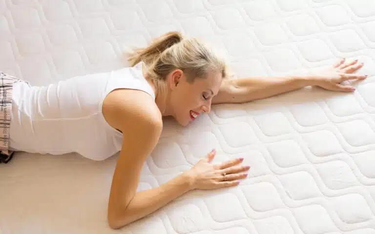 une femme allongée teste la fermeté de son matelas