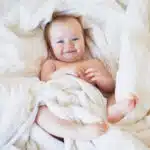 un bébé souriant enroulé dans un linge de lit