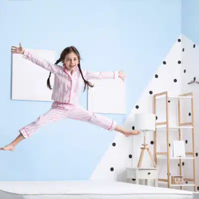 une petite fille saute sur mon matelas les bras en croix