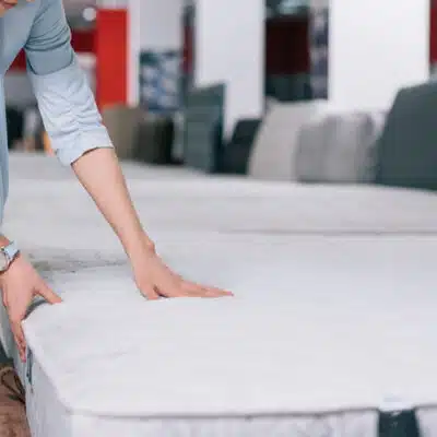 une femme appuie sur un matelas des deux mains