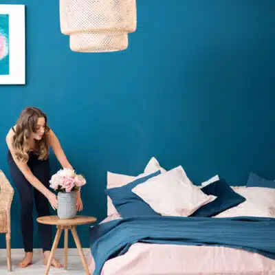 une jeune femme place des fleurs près de son lit