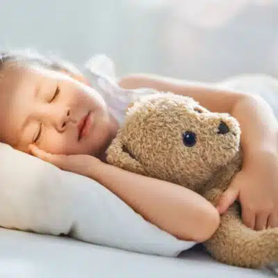 une petite fille dort avec son nounours