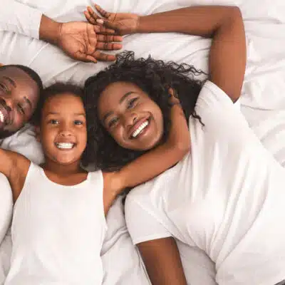 une petite fille au lit avec son père et sa mère