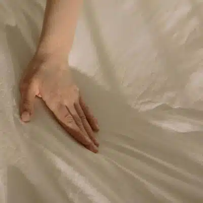 une main qui caresse un drap de lit tout doux