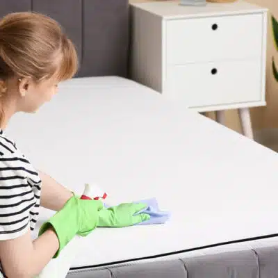 une femme nettoie un matelas avec une éponge