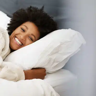 une femme serre son oreiller tout en souriant