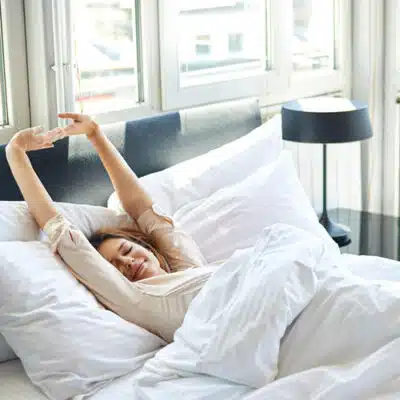 une femme s'éveille et s'étire dans son lit