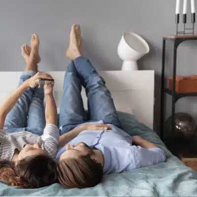 couple au lit pieds en l'air avec smartphone
