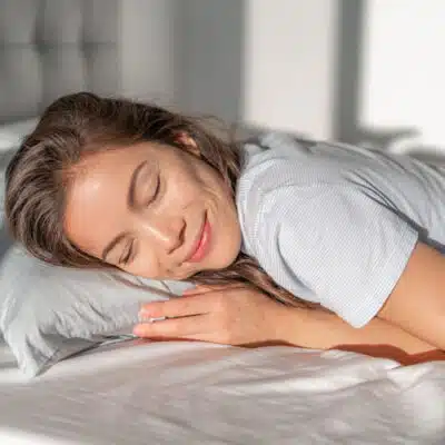 une jeune femme souriante avec la tête sur l'oreiller