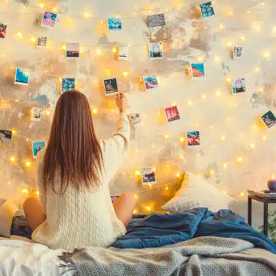 une jeune fille affiche des photos au dessus de son lit