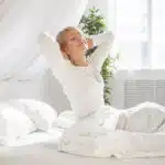 une femme en pyjama blanc se détend après une bonne nuit de sommeil