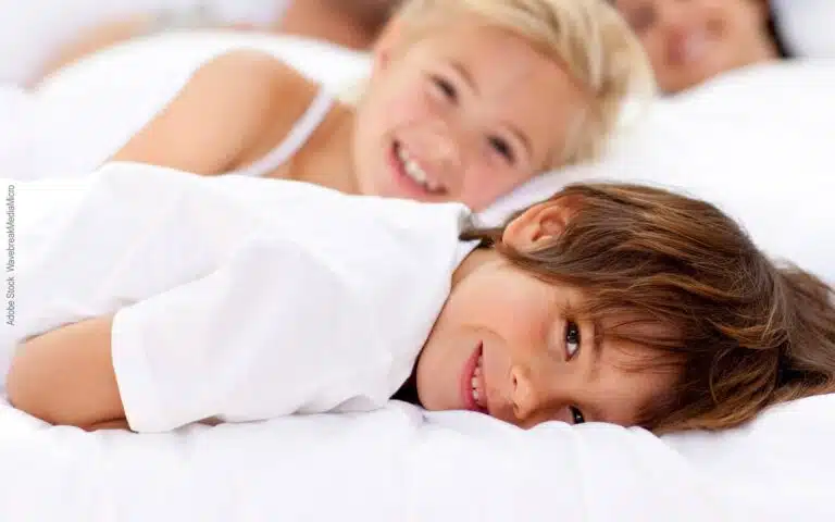 une jeune garçon et sa petite soeur sur un lit