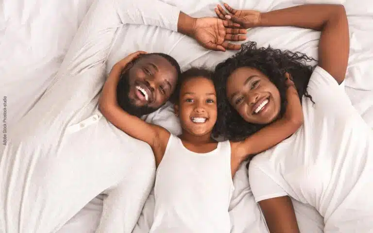 une petite fille et ses parents dans un lit