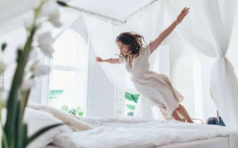 une jeune femme s'élance et saute sur un lit