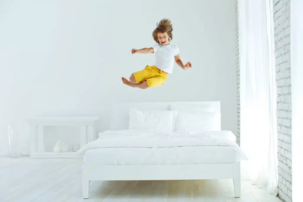 un enfant saute très haut sur un lit