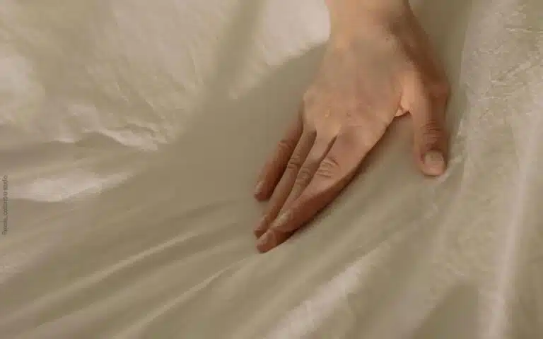 une main glisse sur un drap en lin