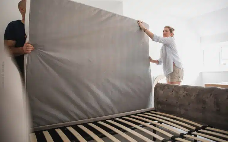 une femme et son mari soulèvent un matelas pour nettoyer le sommier