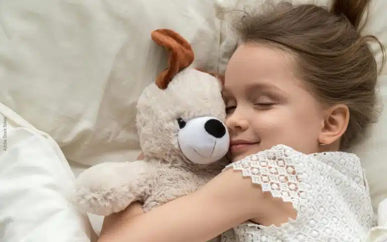 une petite fille serre fort son petit ours