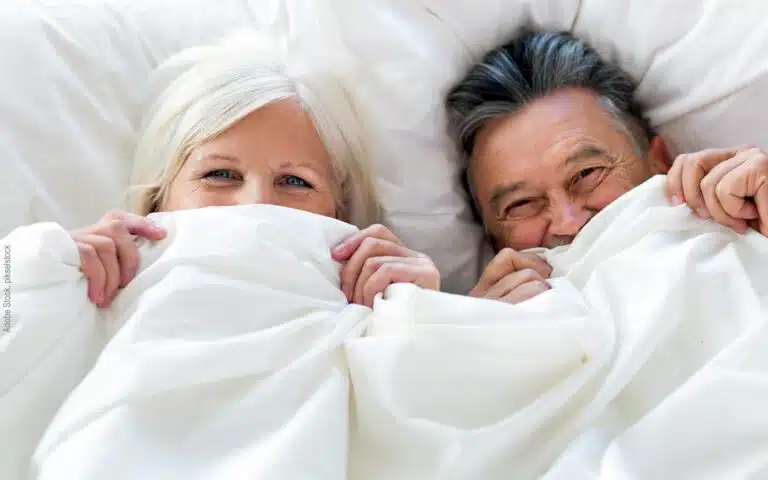 un couple senior rit sous la couette