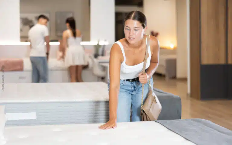 dans un magasin, une jeune femme appuie sur un matelas
