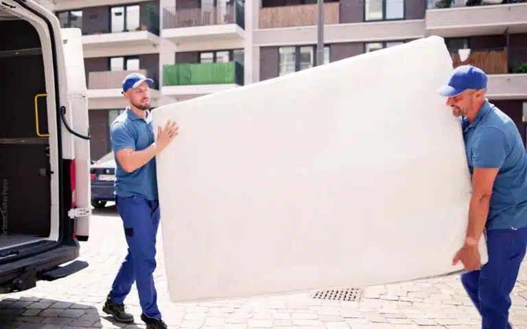 deux livreurs s'occupent d'un vieux matelas