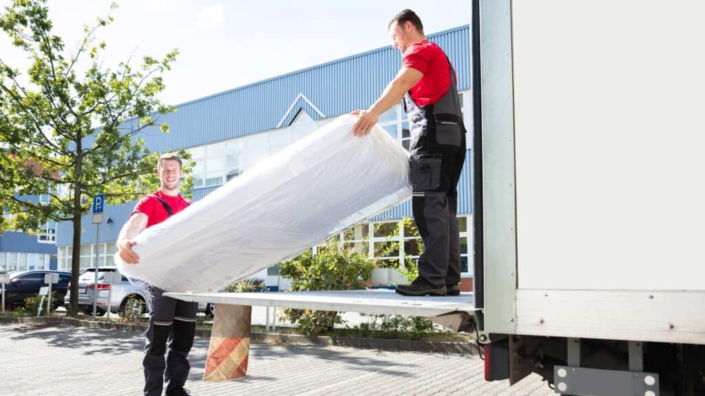Deux livreurs sortent un matelas neuf d'un camion