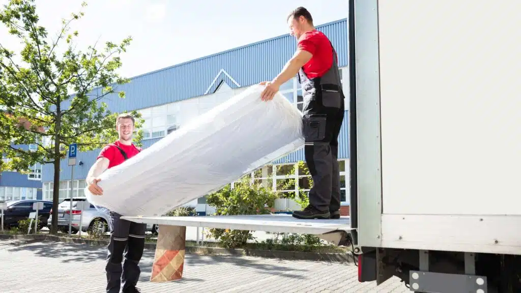 Deux livreurs sortent un matelas neuf d'un camion