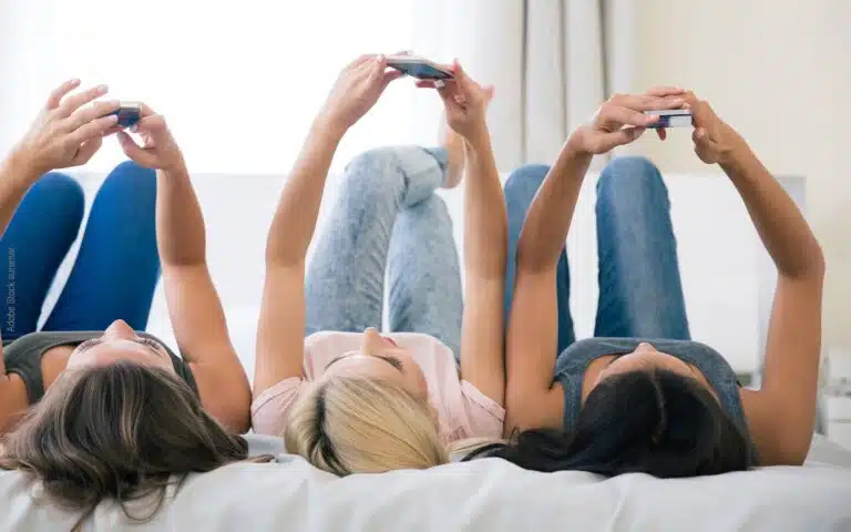 des jeunes filles sur un lit avec leur iPhone