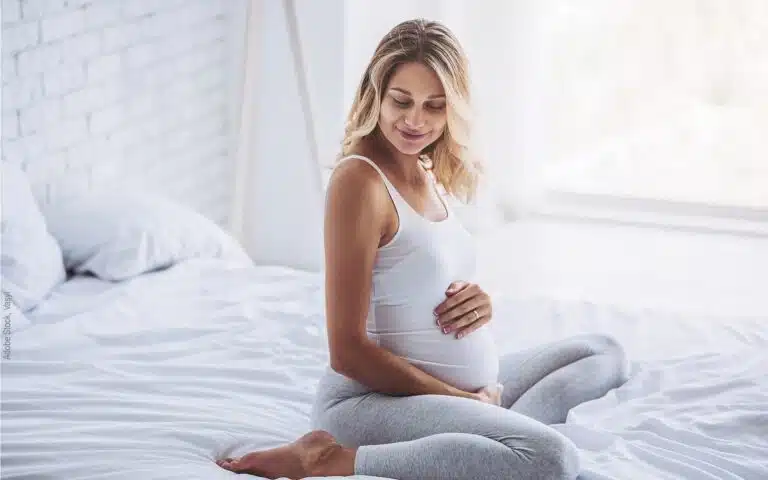 une femme enceinte assise sur son lit
