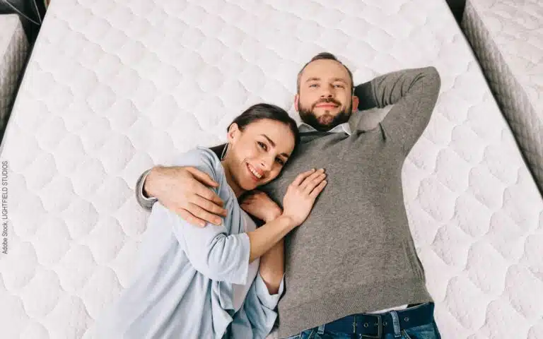 un homme et sa femme en allongés dans un magasin de literie pour tester un matelas